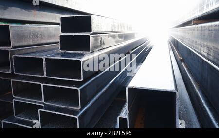 La pila di prodotti metallici laminati si trova in un magazzino, tubi in acciaio a sezione rettangolare, vista prospettica Foto Stock