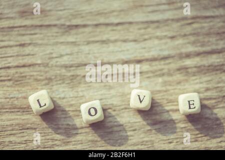Macro PAROLA D'AMORE di lettere bianche dell'alfabeto inglese su asse di legno Foto Stock