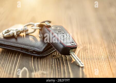 Chiudete le nuove chiavi dell'auto con il portafoglio in pelle nera sul tavolo in legno. Acquisto auto o noleggio auto Foto Stock