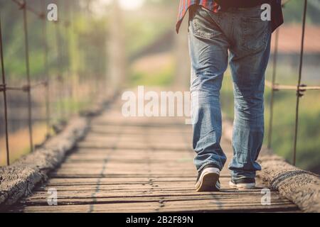 Turista asiatico che cammina sul ponte di legno vecchio e rotto. Rischi del concetto di viaggio Foto Stock