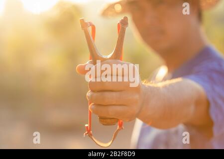 Primo piano uomo che gioca slingshot o catapulta al mattino con effetto luce del sole Foto Stock