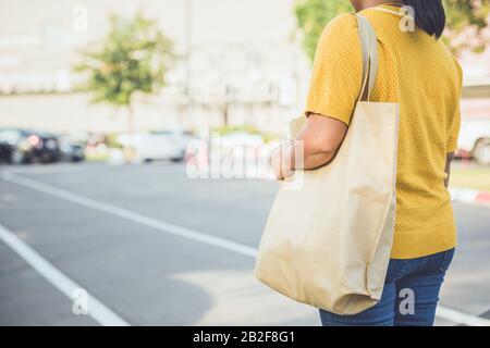 Donna che usa un sacchetto di cotone marrone nel centro commerciale per sostituire l'uso del sacchetto di plastica Foto Stock