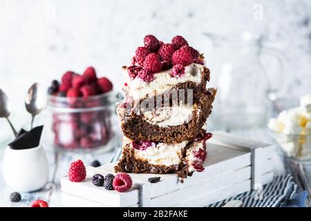 Cheesecake brownies con lampone accatastato su un piatto. Fusione del cioccolato. Pezzo di torta. Dessert brownie. Ciliegia e lampone. San Valentino. Donna Foto Stock