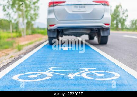 Moderna vettura SUV su strada asfaltata / pista ciclabile e pedata su cartello bianco per bicicletta Foto Stock