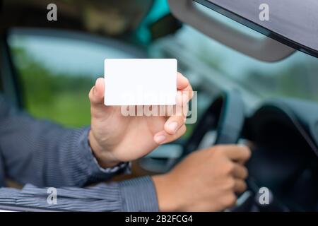 Giovane uomo asiatico seduto nella vettura moderna e senza carta bianca. Per noleggio auto o concetto di business auto Foto Stock