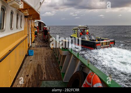 Una barca da lavoro sismica si avvicina al lato di una Nave dell'Escorts nell'Oceano Africano, pronta a completare un'operazione Di trasferimento Del Personale. Foto Stock