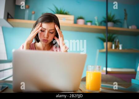 Ritratto di giovani ha sottolineato orinato preoccupato business donna seduta nella parte anteriore del computer portatile Foto Stock