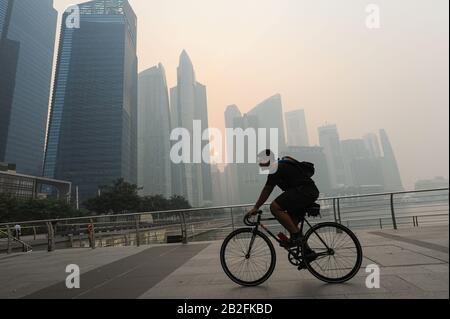 20.06.2013, Singapore, Repubblica di Singapore, Asia - un ciclista combatte il suo cammino attraverso la pericolosa foschia che avvolge il quartiere centrale degli affari. Foto Stock