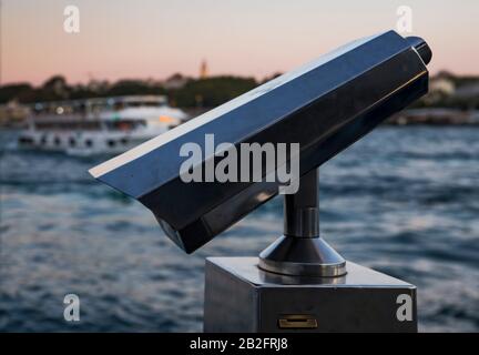 Primo piano del binocolo Coin operato al tramonto sul mare. Foto Stock