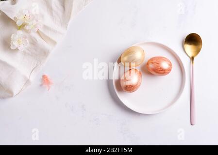 Tavola di Pasqua impostazione dall'alto. Elegante piatto vuoto, posate, tovagliolo e uova d'oro su pietra Foto Stock