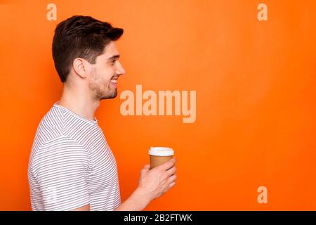 Solo per te. Profilo foto di divertente attraente macho tizio tenere mano caldo takeout caffè bevanda aspetto lato vuoto spazio indossare strisce t-shirt isolato Foto Stock