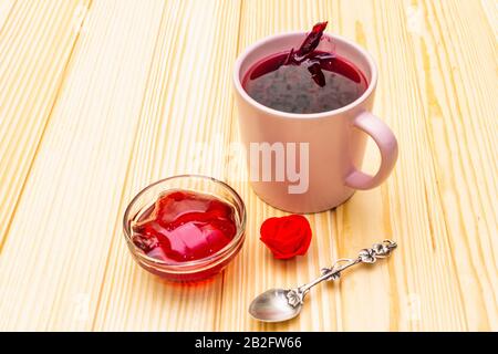 Tè karkade dai petali di ibisco (rosa sudanese). Colazione romantica e delicata. Su uno sfondo di legno, primo piano Foto Stock