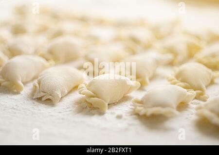 Gnocchi (vareniki) con patate su sfondo bianco - tradizionale cibo ucraino. Cottura di gnocchi crudi con patate. Foto Stock