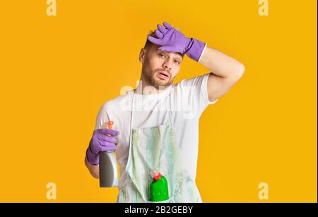 Uomo stanco nel grembiule e guanti strofinano la fronte Foto Stock