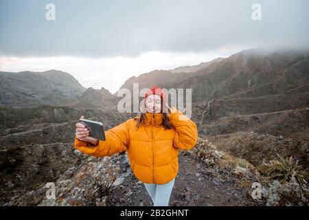 Ritratto di un giovane viaggiatore vestito di giacca luminosa e cappello godendo di un viaggio altamente in montagna, viaggiando sull'isola di Tenerife, Spagna Foto Stock