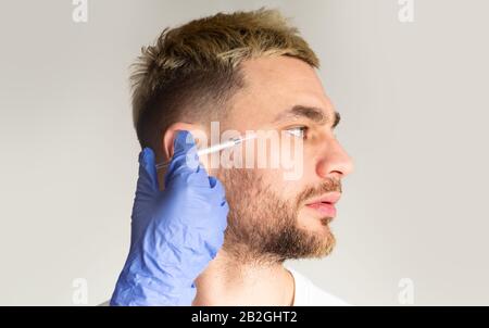 Variazioni di età. Estetista fa iniezioni anti-invecchiamento per l'uomo Foto Stock