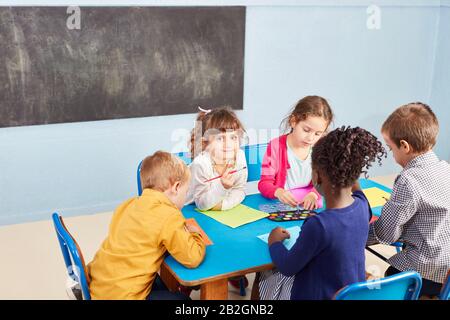 I bambini dipingono nell'asilo con acquerelli e pennelli al tavolo Foto Stock