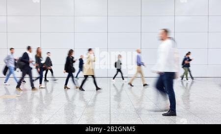 Anonimo gruppo sfocato di gente di affari che va alla conferenza o alla fiera Foto Stock