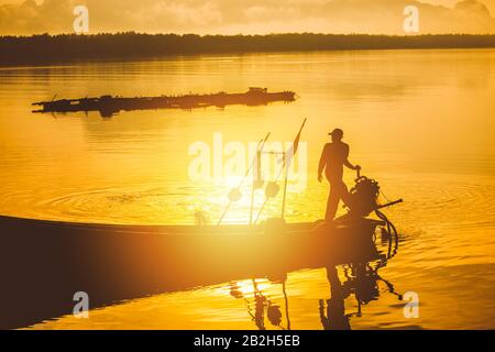 Silhouette di barca da pesca e pescatore al tramonto, Samchong-tai, Phangnga, Thailandia, barca villaggio di pesca, rete e sunrise.Thailand Foto Stock