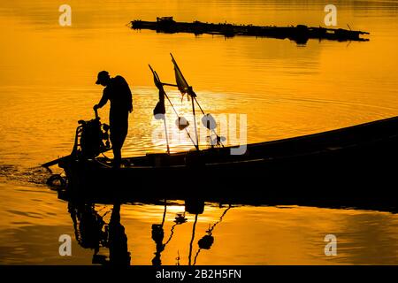 Silhouette di barca da pesca e pescatore al tramonto, Samchong-tai, Phangnga, Thailandia, barca villaggio di pesca, rete e sunrise.Thailand Foto Stock
