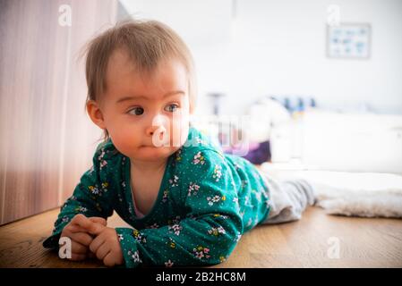 12-15th mese adorabile caucasica ragazza si trovano su pavimento di legno con le mani insieme Foto Stock