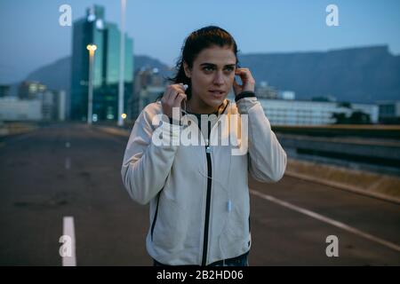 Donna con vista frontale che ascolta la musica mentre corre Foto Stock