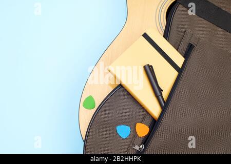 Borsa morbida per chitarra acustica. Tasca leggermente aperta con note, penna e selezione colorata sullo sfondo blu. Vista dall'alto con spazio di copia Foto Stock