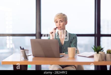 Imprenditore Femminile Che Pensa Seduto Al Laptop Che Lavora In Ufficio Moderno Foto Stock