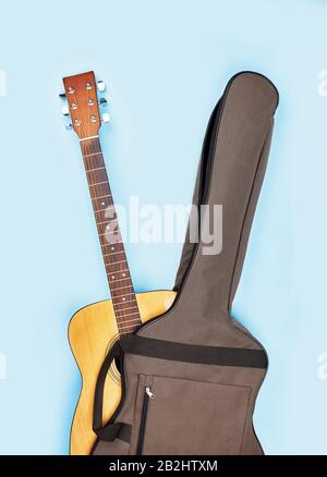 Borsa morbida per chitarra acustica marrone con acustica leggermente aperta su sfondo blu. Vista frontale Foto Stock