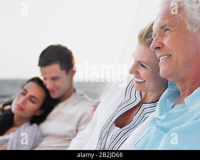 Coppia giovane e di mezza età rilassarsi su yacht concentrarsi sulla coppia di mezza età Foto Stock