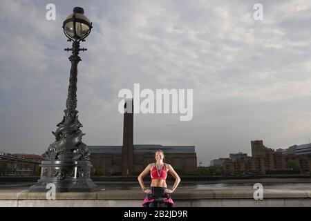 Atleta Triathlon che indossa medaglia d'oro in piedi contro terrapieno del fiume Londra Inghilterra Foto Stock