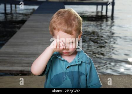 Little Boy Su Pier Strofinando Gli Occhi Foto Stock