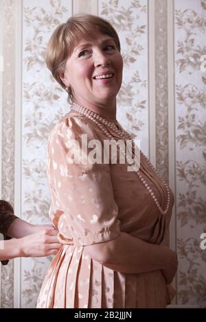 La donna matura attende mentre il suo vestito è fissato Foto Stock
