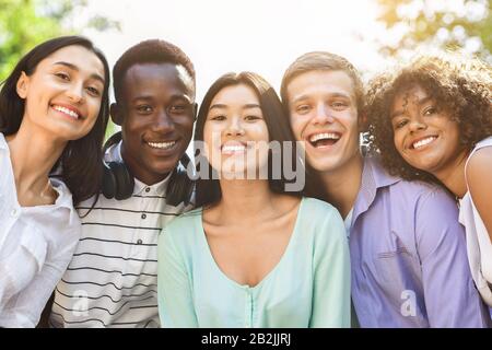 Ritratto di allegri teen amici interracial che posano alla macchina fotografica all'aperto Foto Stock