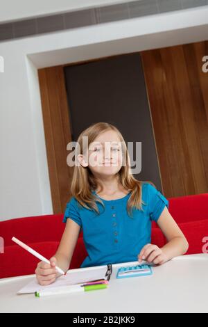 Ritratto di una ragazza felice che fa i compiti a tavola Foto Stock