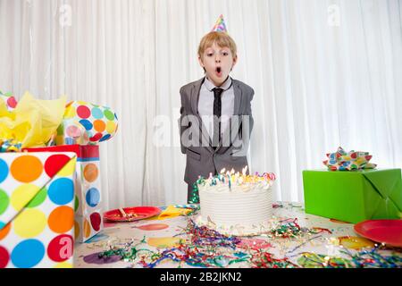 Pre-teen compleanno ragazzo che soffia candele sulla torta Foto Stock