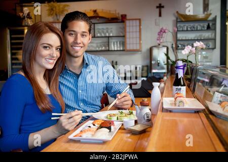 Ritratto di giovane coppia che mangia cucina giapponese nel ristorante Foto Stock