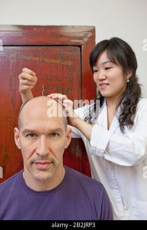 Donna asiatica acupuncturist che dà l'uomo maturo trattamento giapponese Foto Stock