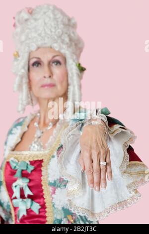 Ritratto della regina più anziana che allunga la sua mano su sfondo rosa Foto Stock
