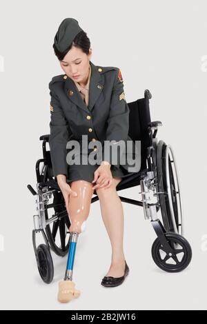 Ufficiale militare statunitense femminile in protesi calzata su sedia a rotelle piede su sfondi grigi Foto Stock