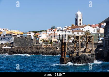 Resti del vecchio molo di Garachico con il campanile bianco della chiesa di Santa Ana dietro, Tenerife, Isole Canarie, Spagna Foto Stock