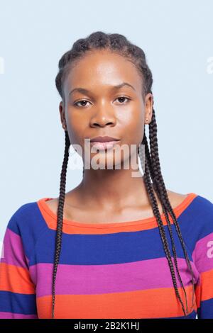 Ritratto di una giovane donna seria con capelli intrecciati su sfondo azzurro Foto Stock