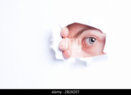 Giovane donna asiatica che peeking dal buco di carta strappato Foto Stock