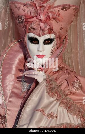 Venezia, febbraio 19 2020. Primo piano della donna in maschera decorata e costume rosa ornato posa per la macchina fotografica a Piazza San Marco Foto Stock