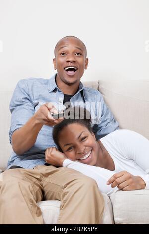 Giovane ed entusiasta coppia afroamericana che guarda la TV Foto Stock