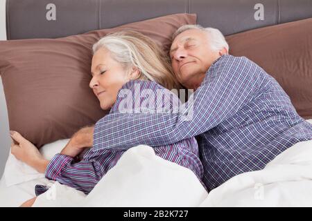 Romantica coppia senior che dorme sul letto a casa Foto Stock