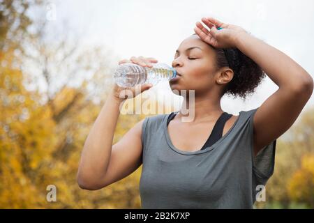 Sporty giovane donna acqua potabile in posizione di parcheggio Foto Stock
