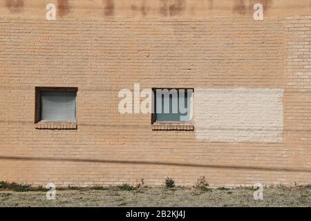 un paio di finestre quadrate vintage sulla facciata di un edificio di magazzini in mattoni marroni Foto Stock