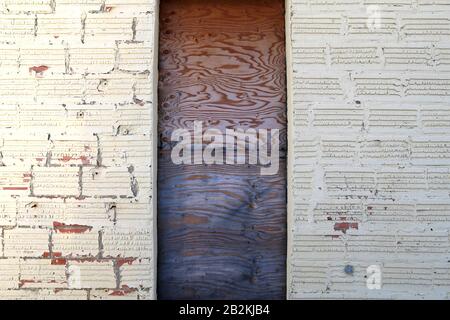 un vecchio edificio dipinto di bianco con pareti dipinte di bianco e una porta in legno Foto Stock