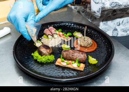 Lo chef del ristorante prepara un piatto, termina il piatto su un piatto Foto Stock